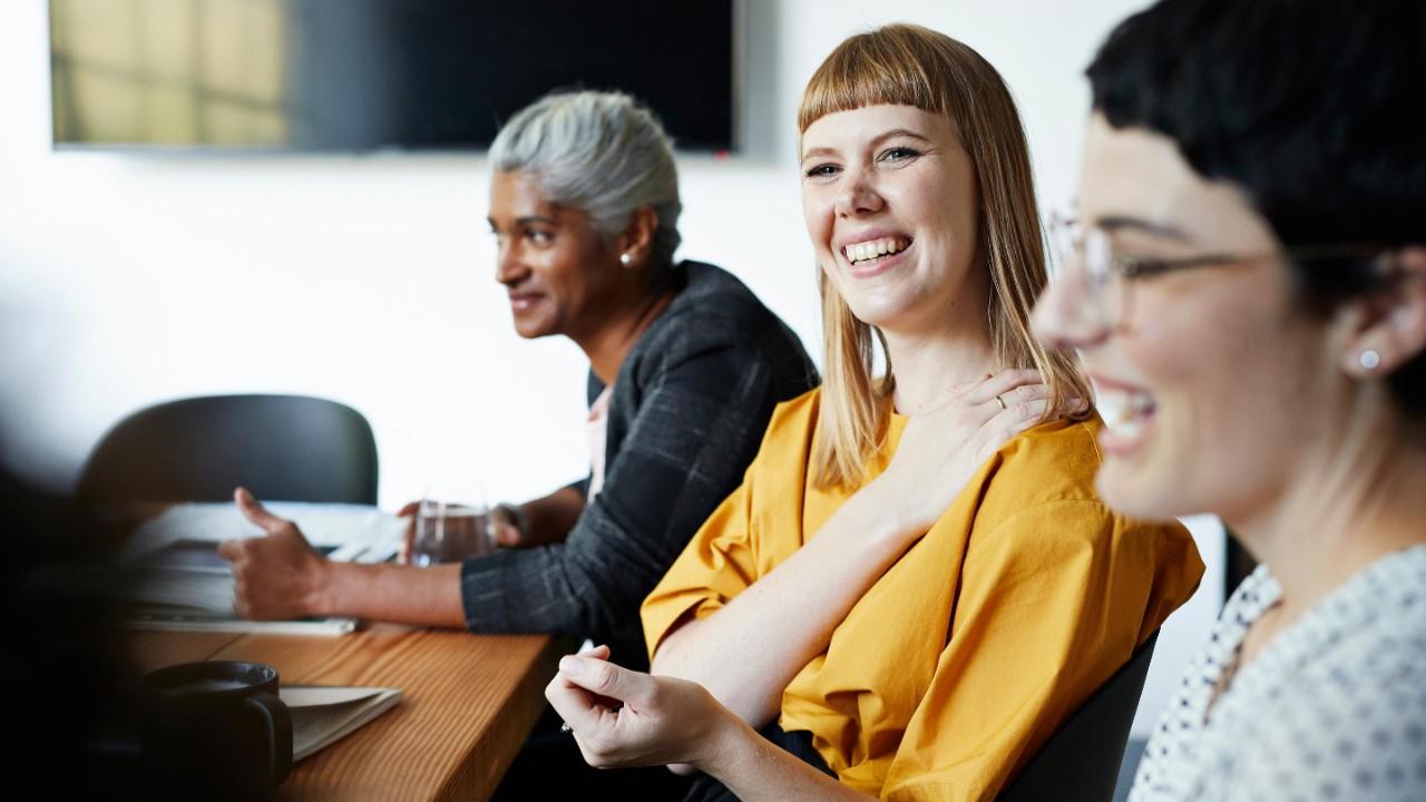 微笑的企业家和女同事在工作场所开会时看向别处